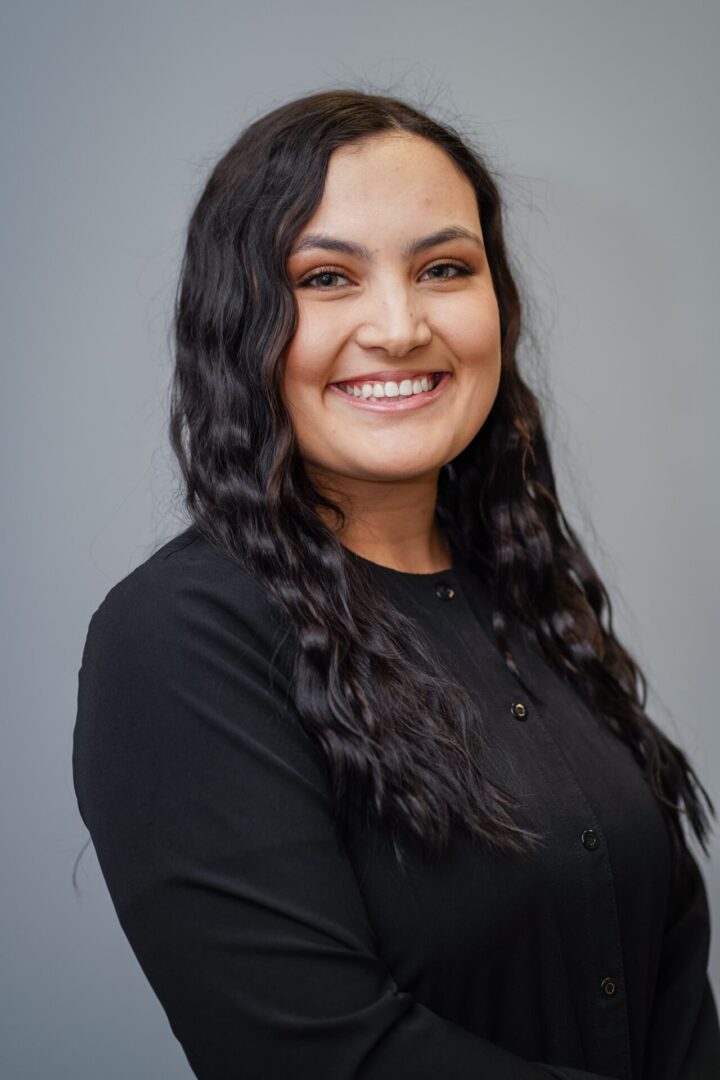 A woman with long black hair smiles for the camera.