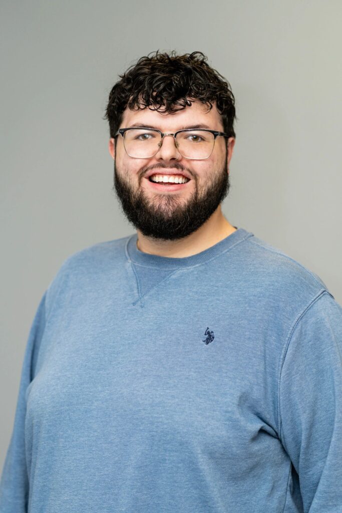 A man with glasses and beard smiling for the camera.